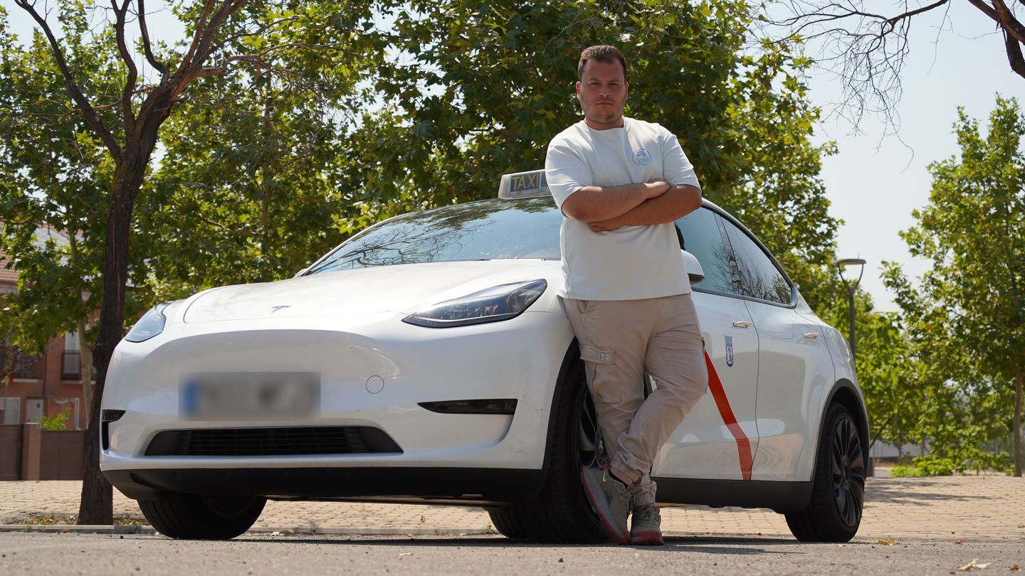 Jorge Cristóbal Román (JCTaxielectrico) con los brazos cruzados junto a su taxi eléctrico, un Tesla Model Y blanco